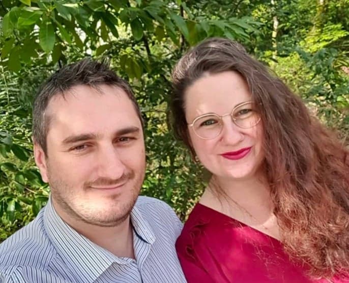 Barbara and Kevin smiling in the shade of a tree.