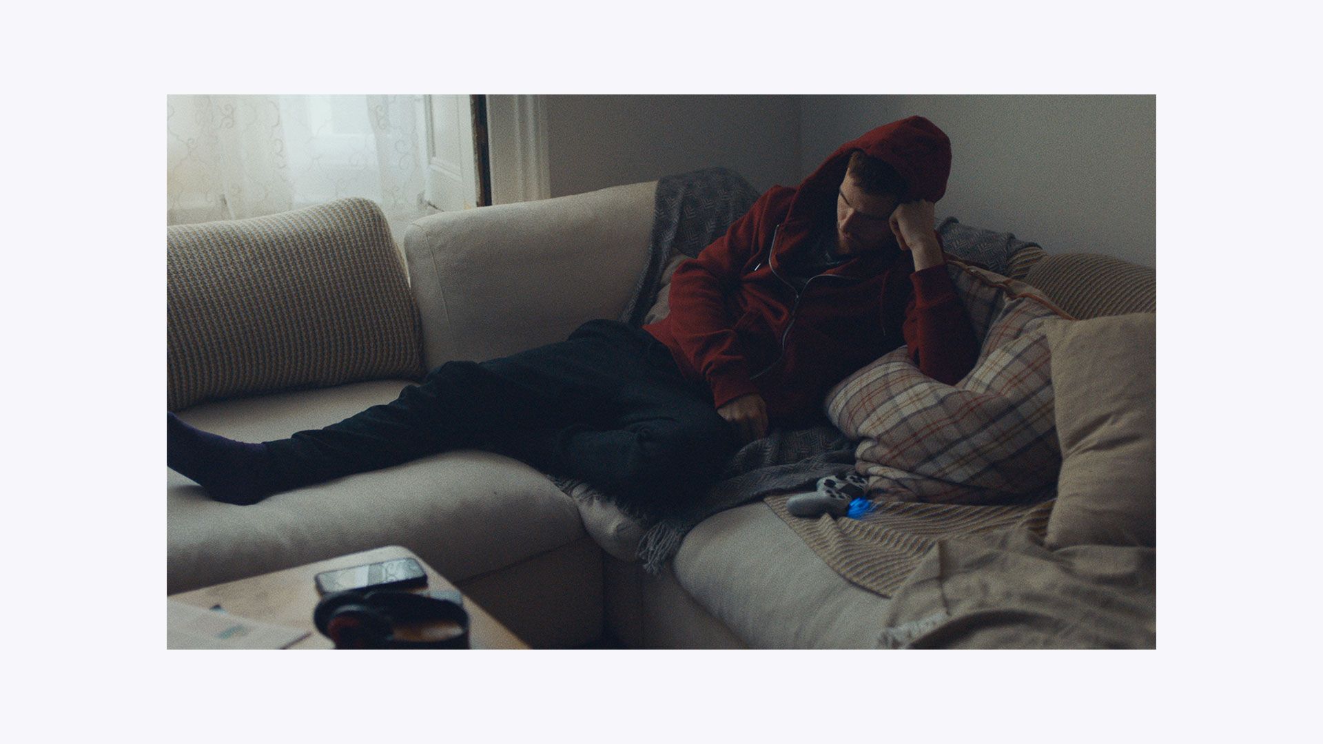 A man sitting on the couch playing video games, looking deflated.