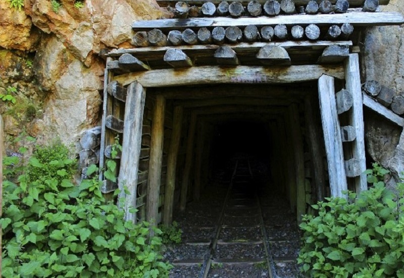 An entrance to an abandoned mine in the side of a rock formation. The tunnel leads to an underground coal mine.