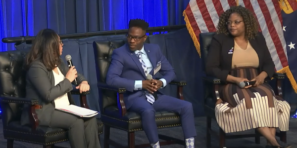 Three people sit on a stage, having a panel conversation.