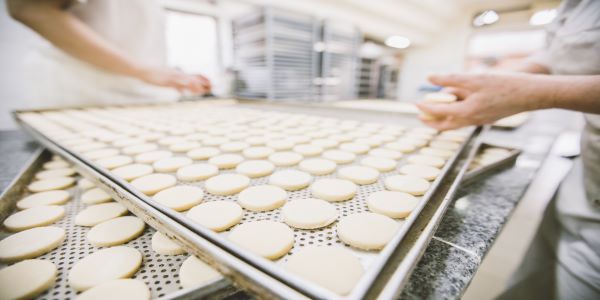 A cookie sheet covered in rows of cookie dough in an industrial kitchen