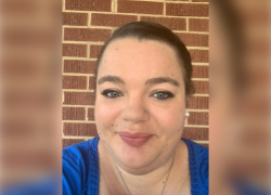 Headshot of Melyssa Scott, smiling in front of a brick wall