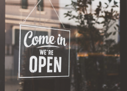 A vintage sign reading 'come in, we're open' hangs in a shop's door