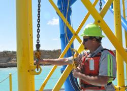 A miner stands on equipment at a surface mine.