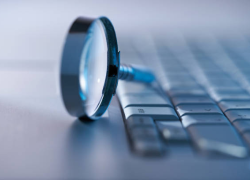 A magnifying glass on a computer keyboard.