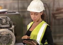 Woman wearing a hardhat and vest. 