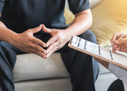 Close-up of a man consulting with a medical professional who holds a clipboard.