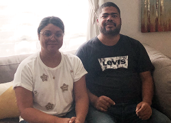 A man and a woman sit on a couch in a living room. 