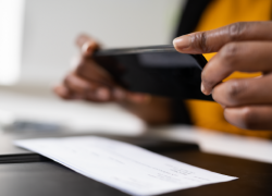 A person snaps a photo of a check with a cell phone. 