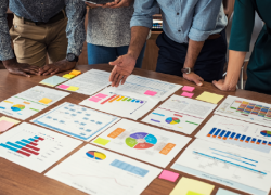 Coworkers look at charts spread out on a table