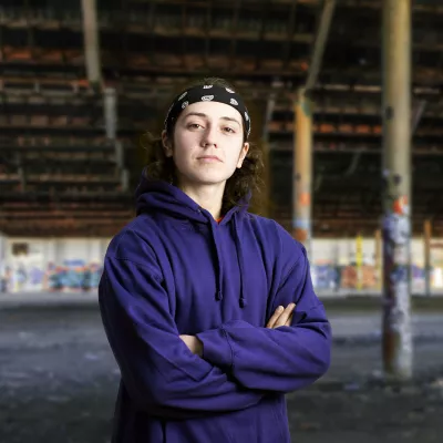 Young person in blue hoodie with arms crossed