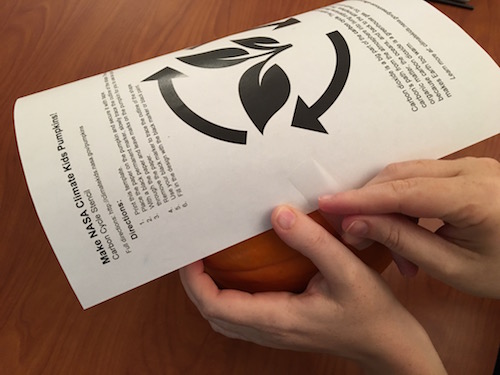 A paper template taped to a pumpkin