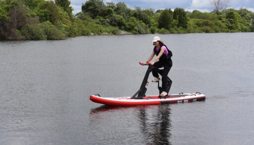 A woman on a paddleboard-bike on the water