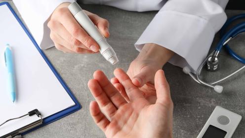 Close-up of physician using lancet to draw blood for blood glucose test