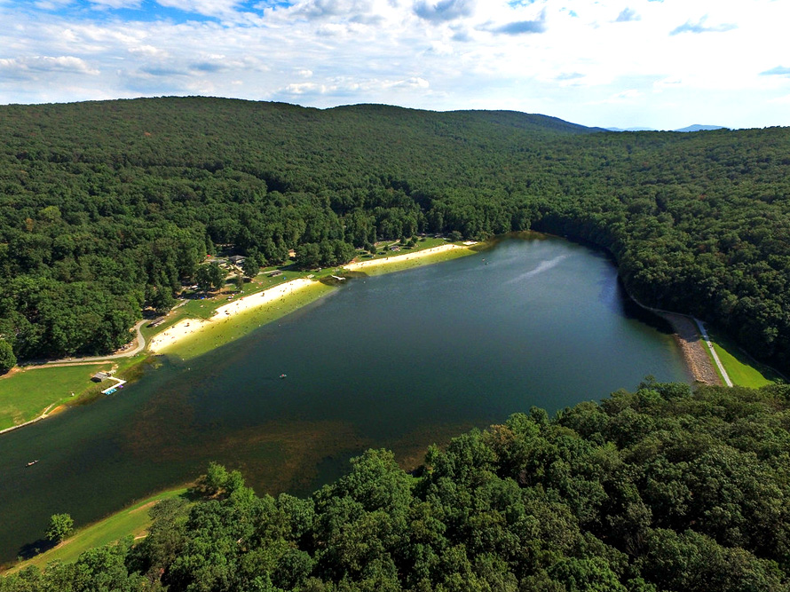 Sky view of the park, vast blue lake surrounded by mountains and trees as far as you can see