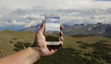 Person with an outreached hand holding a phone using the NASA GLOBE Observer app