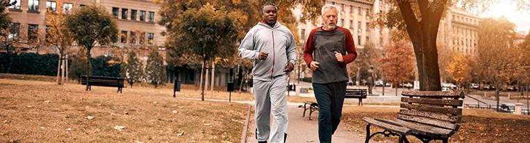 Two men jog in a city park.