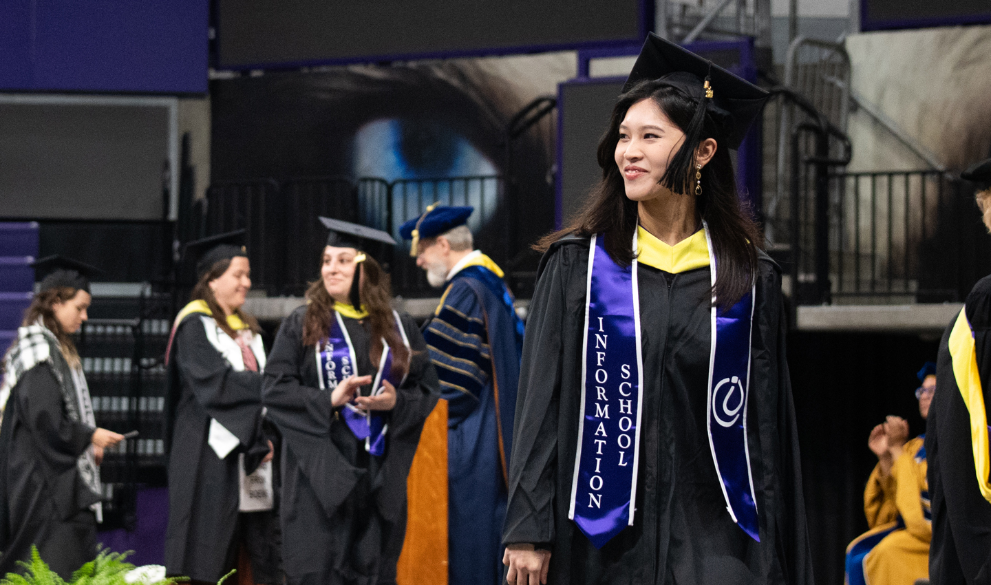 A woman walks across the stage at Convocation