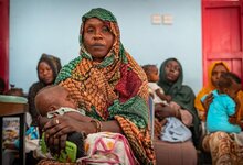 Bambina dorme tra le braccia della madre mentre aspetta il turno per effettuare le misurazioni nel centro sanitario sostenuto dal WFP a Port Sudan. Foto: WFP/Abubakar Garelnabei