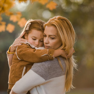 Una niña pequeña se aferra a su mamá en un momento de ansiedad de separación.