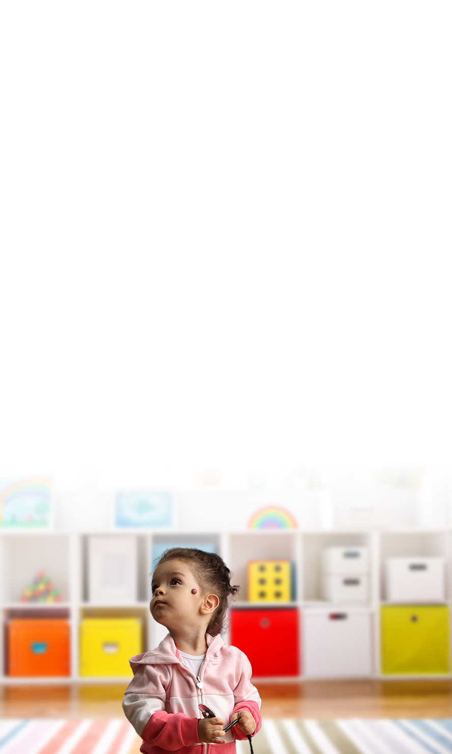 Preschooler with hemangioma on her left cheek holds her doctor's stethoscope at an office visit