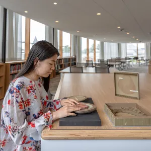 Student working with a rare book in the Special Collections reading room.