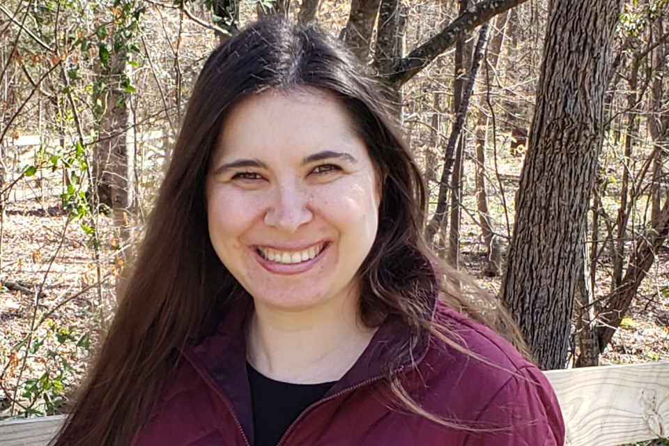 Smiling woman outside in front of many trees