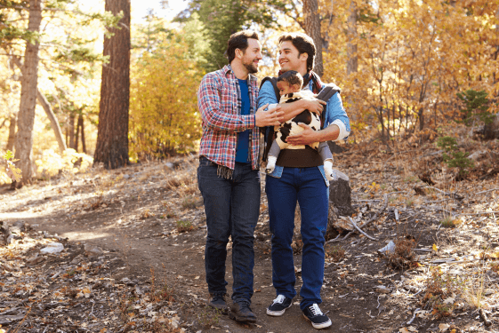 Two men walking outside with a baby.