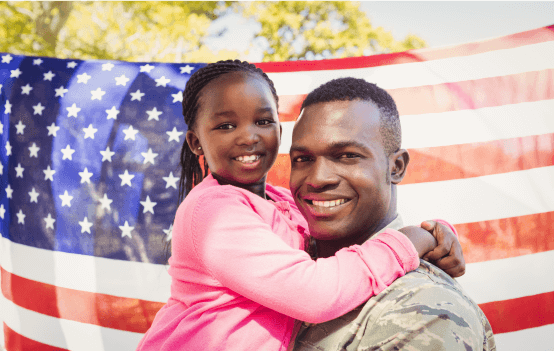 Smiling veteran in uniform holding his daughter.