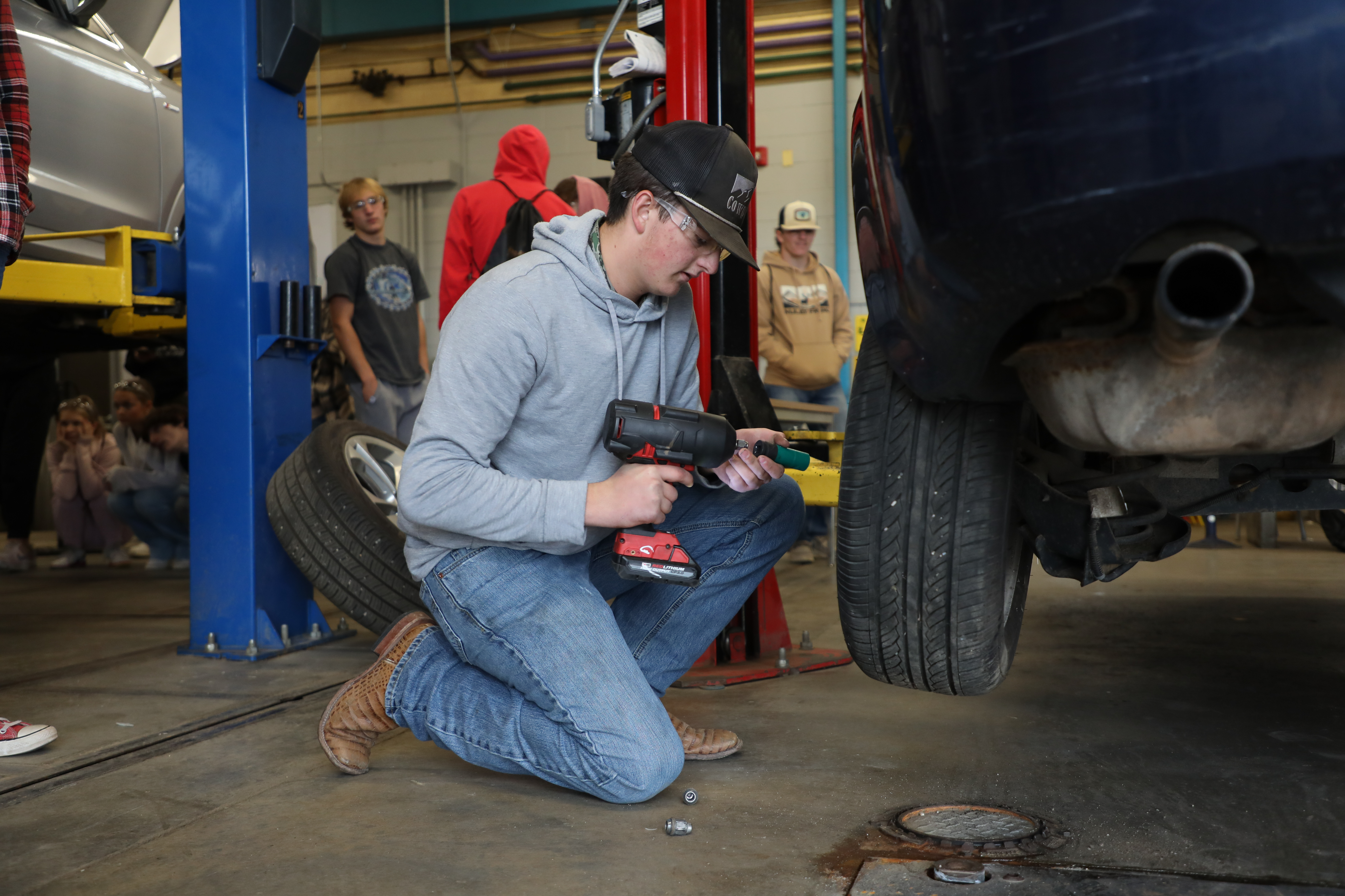 A student changes a tire for Trades and Technology Day