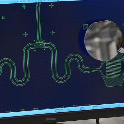 Researcher facing away from camera in a suit and goggles holds up a reflective circle, a piece of scientific equipment engineered at the University of Chicago