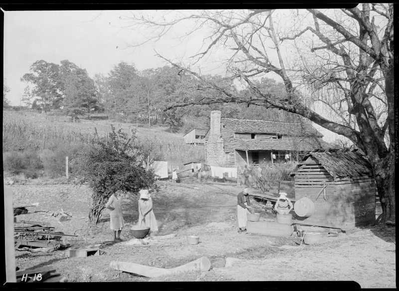 Stooksberry family members was clothes in large wash basins in front of their civil war era home. 