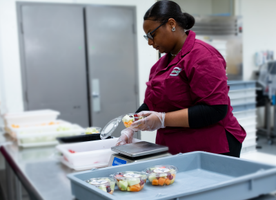 An employee packaging fruit in the new compostable plastic containers