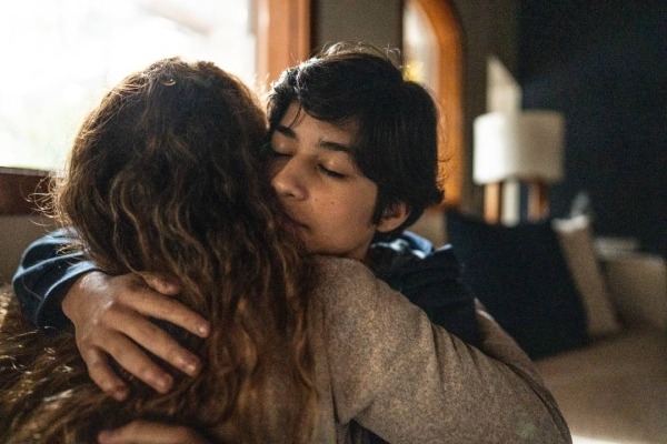 Close-up of young adult man sitting on the couch hugging a woman.