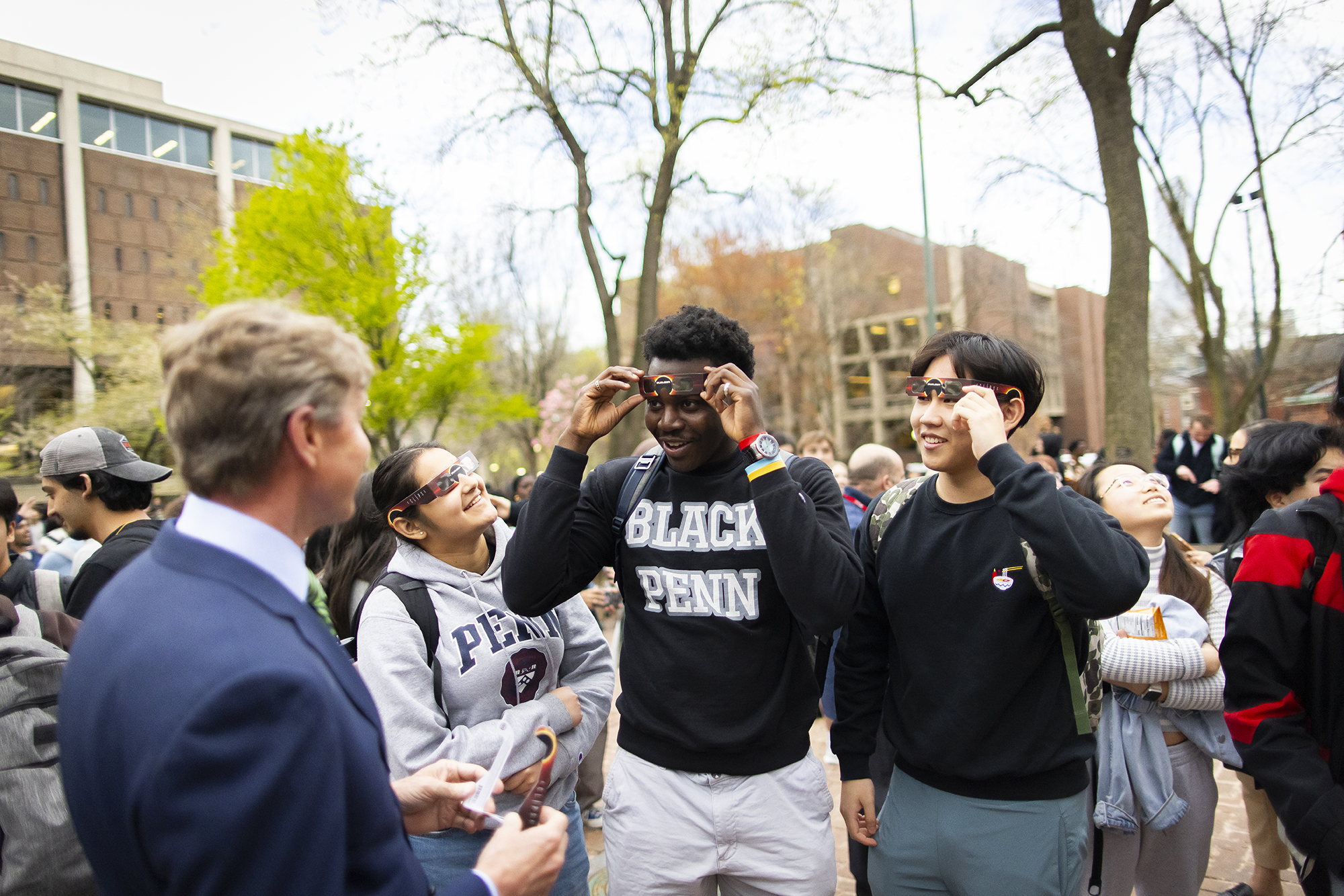 Penn interim president J. Larry Jameson and other students in eclipse glasses on Locust Walk during the solar eclipse.