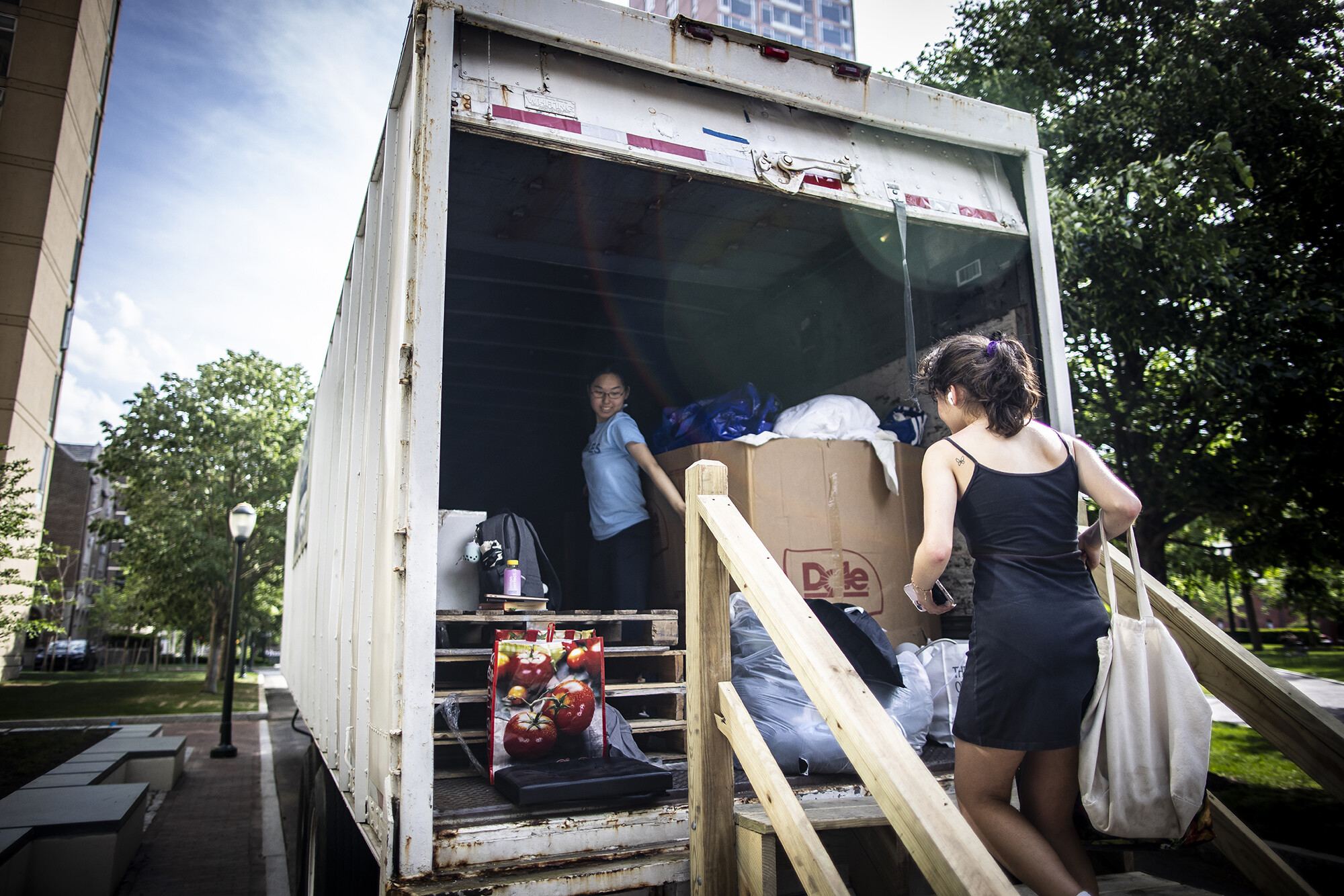 Person brings bag up steps to donation truck. Student volunteer inside, helping