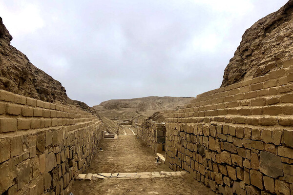 Archaeological site filled with stacked, dusty, aged bricks and surrounded by rocks..