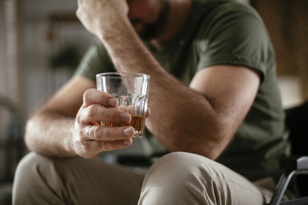 A veteran drinking alcohol in a wheelchair.