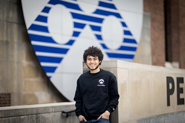 Mostafa Afr standing in front of the Penn shield on Penn Commons.