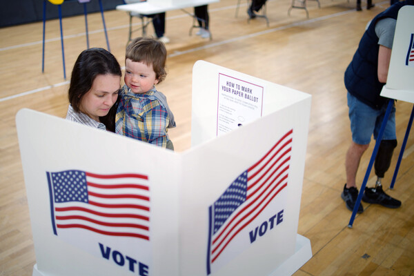 A parent holding a baby voting at a polling place. 