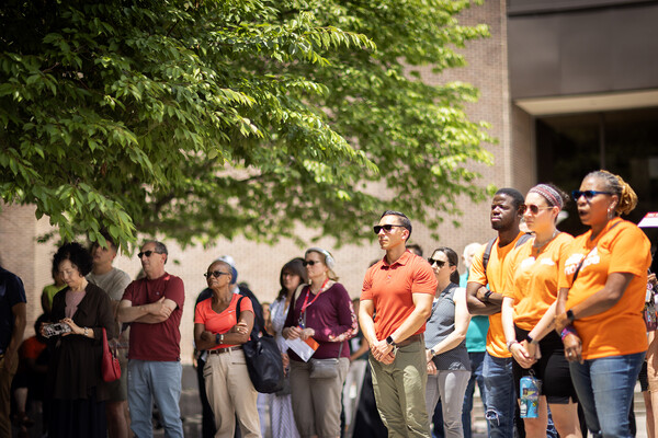 People gathered outside appearing solemn and wearing orange.