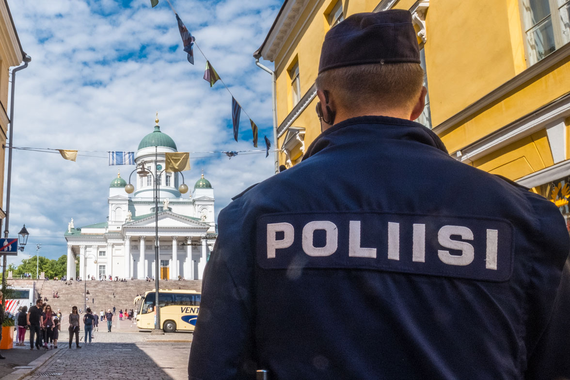 Etualalla konstaapeli selin, mukulakivikatu jatkuu kuvassa kohti Senaatintoria ja Tuomiokirkko näkyy.