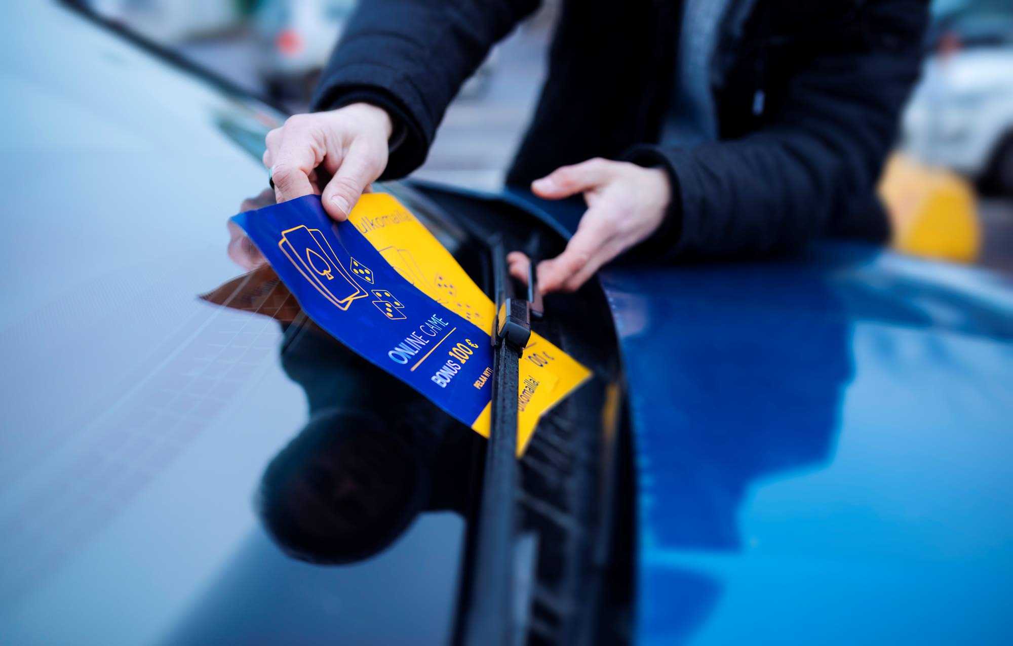 A person puts a flyer about gambling under a windshield wiper.