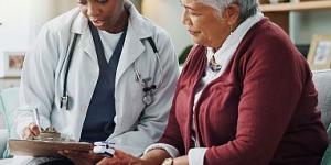 Elderly Latina woman speaking to a young Black woman doctor.