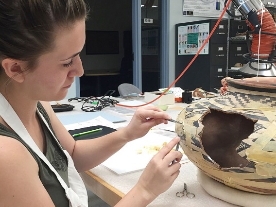 Art conservationist Sophie Church handles a piece of pottery at the Arizona State Museum. 