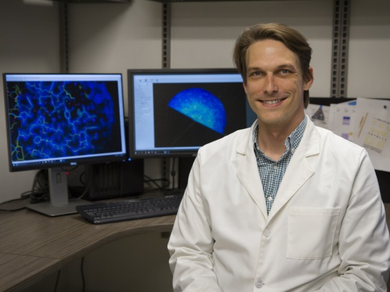 Thomas Moon sits in front of two computer screens in the lab.