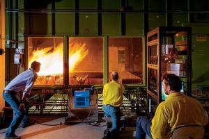 Three people looking into a lab with a large flame