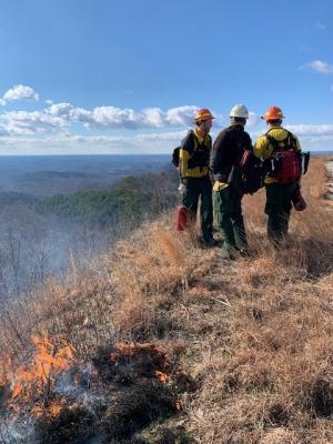 people stand on a hill and prepare to start a prescribed fire 