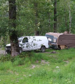 Van attached to mobile home alongside a road through the forest.