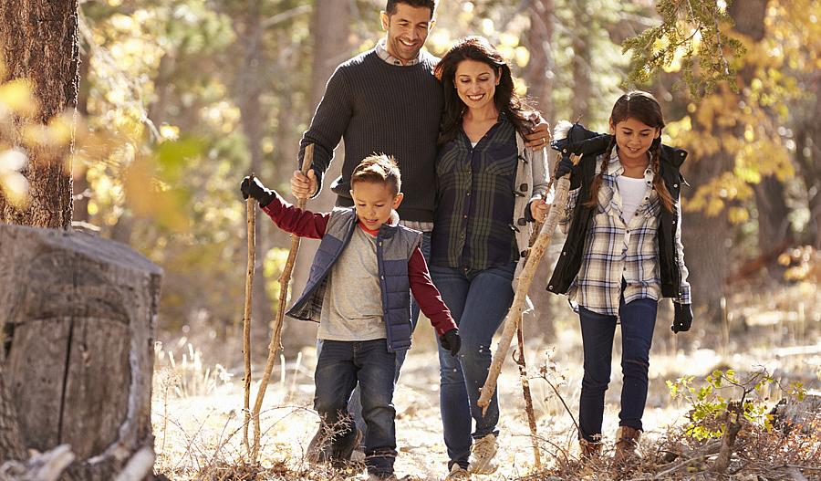 Familia feliz con dos niños caminando en un bosque